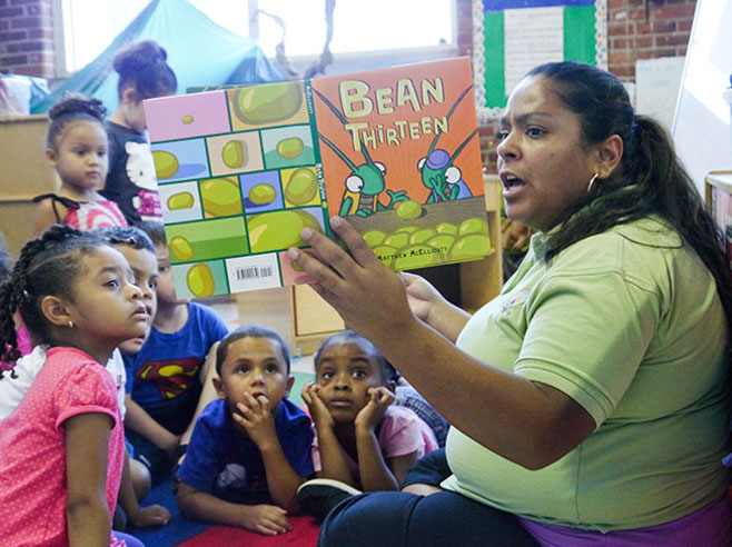 A teacher reads the book Bean Thirteen aloud to a group of preschool children.