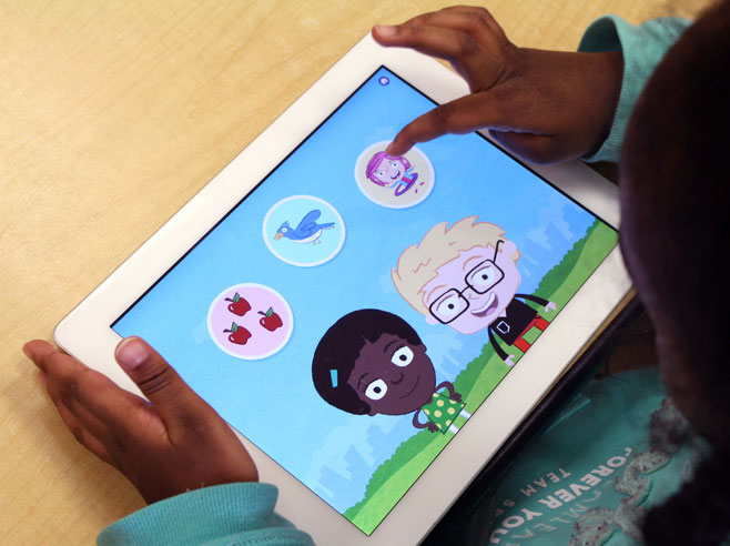 A young girl holds an iPad showing the Gracie and Friends Park Play app on-screen.