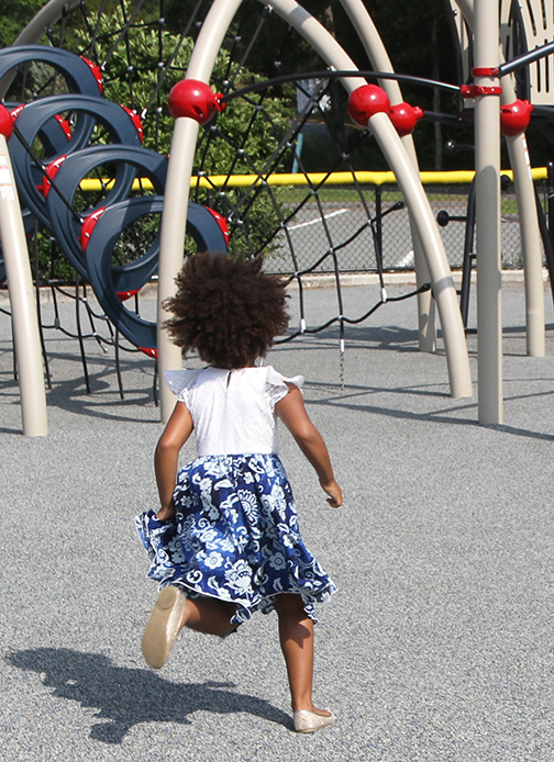 A young girl runs across a playground.