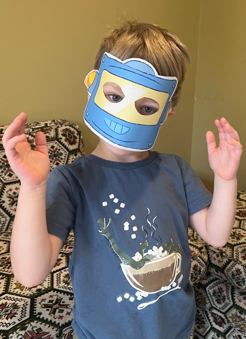 A young boy wears a printed out blue robot mask.
