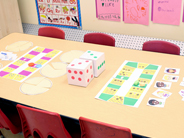 The Park Play Board Game is set up on a table with six red chairs in a preschool classroom.