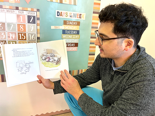 A man holds up and reads David Elliot’s book “Henry’s Map.”