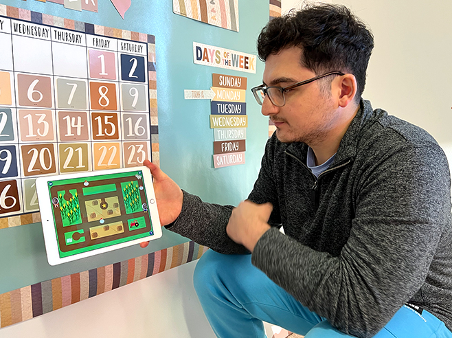 A man models playing goat challenge game in the Gracie & Friends “Map Adventures” preschool spatial thinking app.
