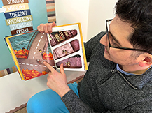 A man points to a raccoon on the page of a book while he reads Julie Dillemuth’s book “Lucy in the City.”