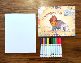 Julie Dillemuth’s book “Mapping My Day” next to a stack of paper and a pile of markers.