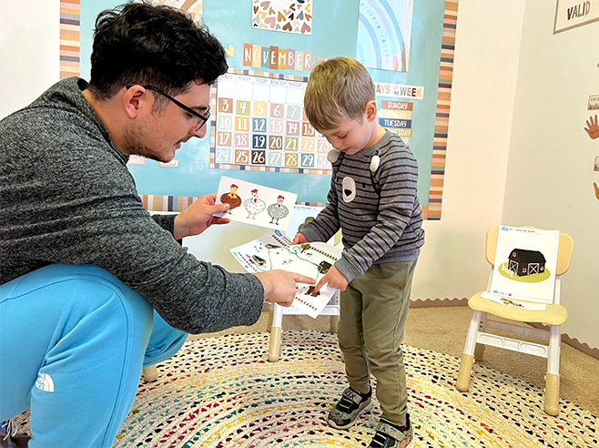 A man and a boy point to landmarks on a printout of a farm map in a preschool classroom.