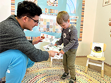 A man and a boy point to landmarks on a printout of a farm map in a preschool classroom.