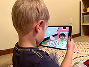 A boy views a digital farm scene through an iPad as he plays the Gracie & Friends “AR Adventures” augmented reality app.