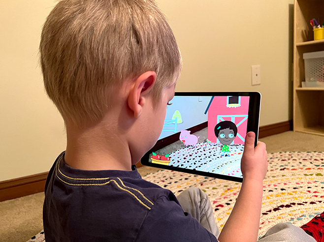 A boy views a digital farm scene through an iPad as he plays the Gracie & Friends “AR Adventures” augmented reality app.