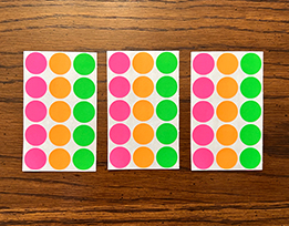 Sheets of brightly colored dot stickers on a table.