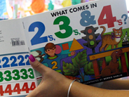 A teacher holds up the book What Comes In 2s, 3s & 4s?