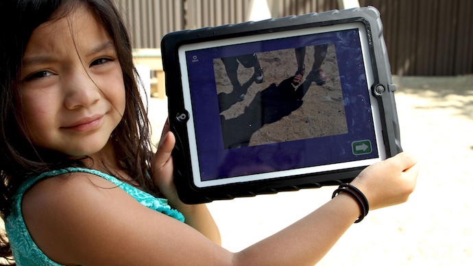 A preschool girl showing a photograph of shadows she took with the app.