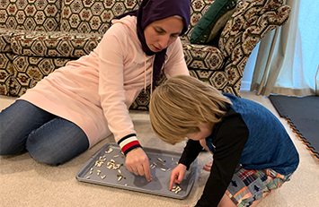 Parent and child sorting seeds on a baking sheet.