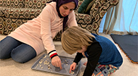 Parent and child sorting seeds on a baking sheet.