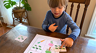 Child placing a card on a game board.