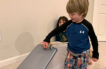 Child rolling a spice jar down a baking tray.