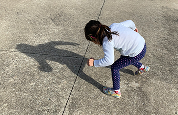 Child making a shadow while posing outside.