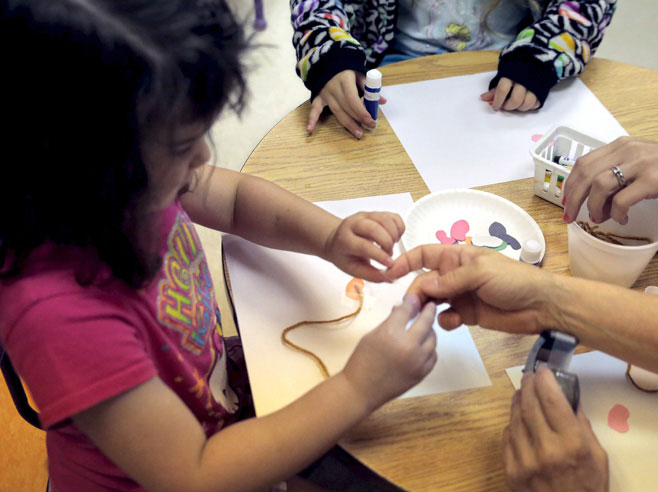 Student tapes yarn to a piece of paper.