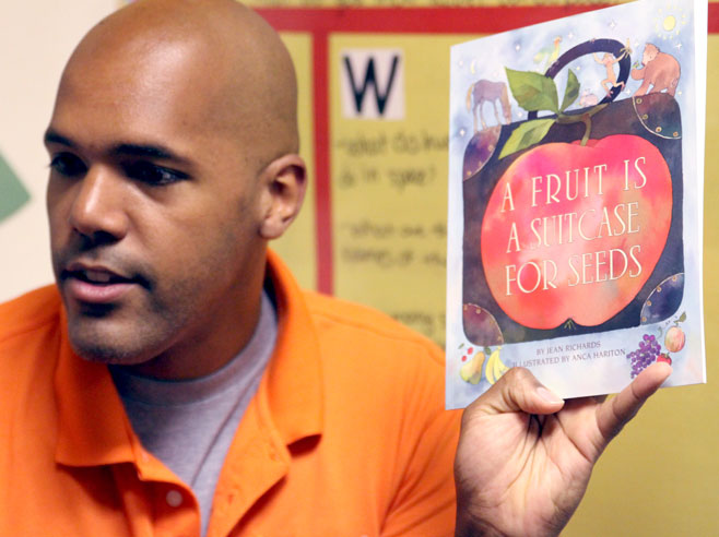 Teacher holds up the book 'A Fruit is a Suitcase for Seeds'