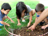 Students explore dirt surrounded by a hula hoop.