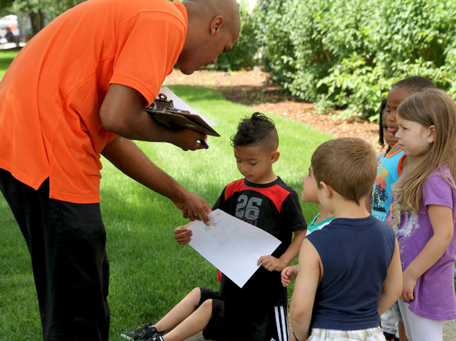 Teacher hands out scavenger hunt materials to students.