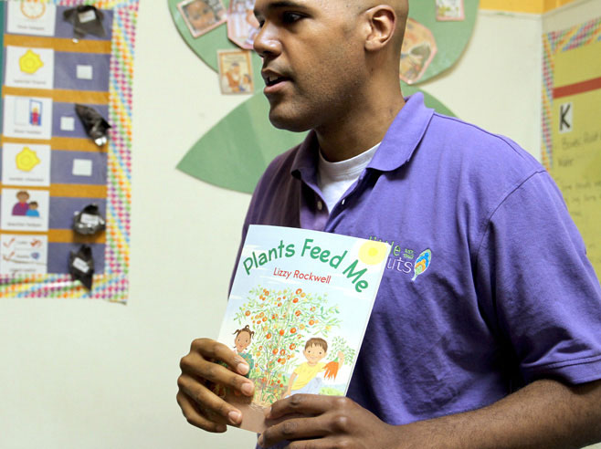 Teacher holds up the book 'Plants Feed Me'.