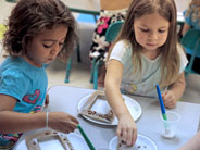 Two students decorate picture frames with seeds.