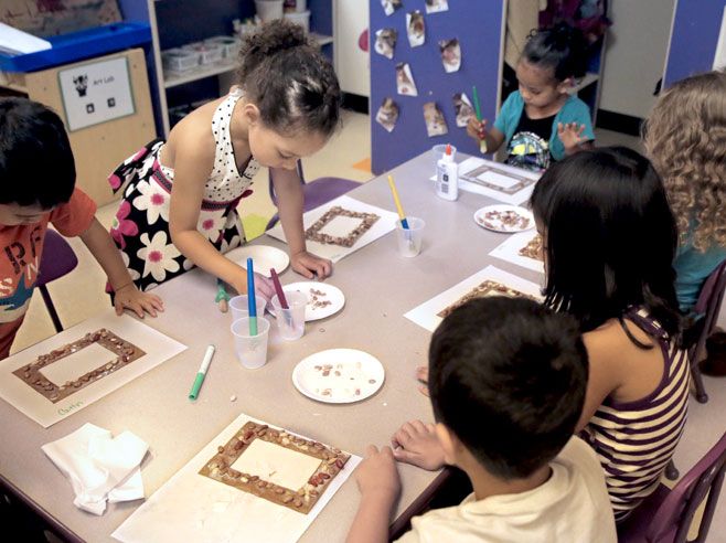 Students glue seeds on their picture frames.