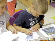 A student sits coloring a piece of paper.