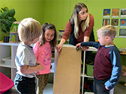 Teacher and students test a cardboard ramp.