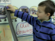 A student prepares to send a marble down a foam half-pipe ramp.