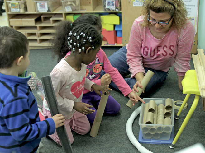Students and teacher examine cardboard tubes.