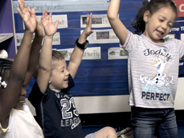 Students close their eyes and wave their arms in the air.
