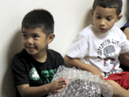 A seated student feels a piece of bubble wrap as another student looks on.