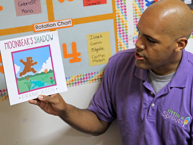 A teacher holds up the book, 'Moonbear's Shadow'.