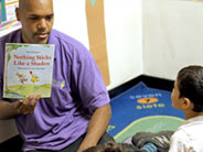 A teacher holds up the book, 'Nothing Sticks Like a Shadow', as a student looks on.