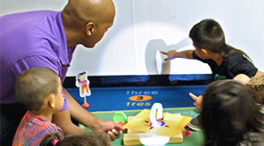 Teacher shining flashlight on object.