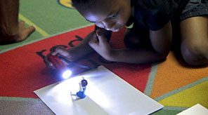 Student shining flashlight on object.