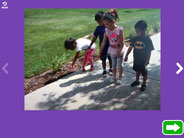 An iPad screenshot showing a photo of four students, outside on a sidewalk, pointing at their own shadows.