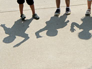 The shadows of three students can be seen, on a sidewalk outside.